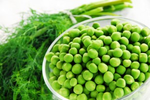 Fresh green peas and herbs in a bowl.