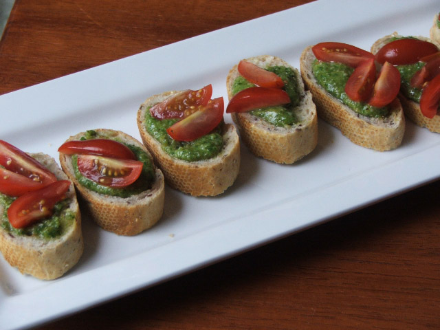 Sliced bread topped with pesto and tomatoes.