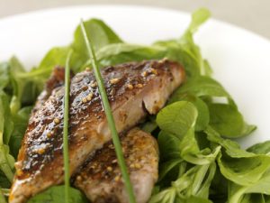 Grilled fish on a bed of greens.