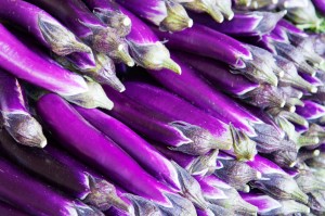 Fresh purple eggplants stacked together.