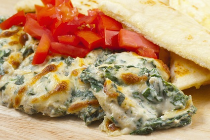 Creamy spinach dish with tomatoes and flatbread.