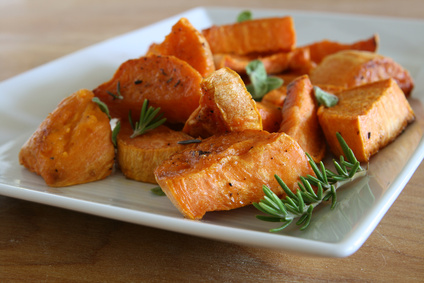 Roasted sweet potatoes with herbs on plate.