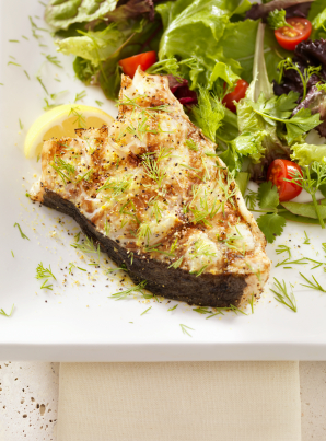 Grilled fish with salad and lemon garnish.