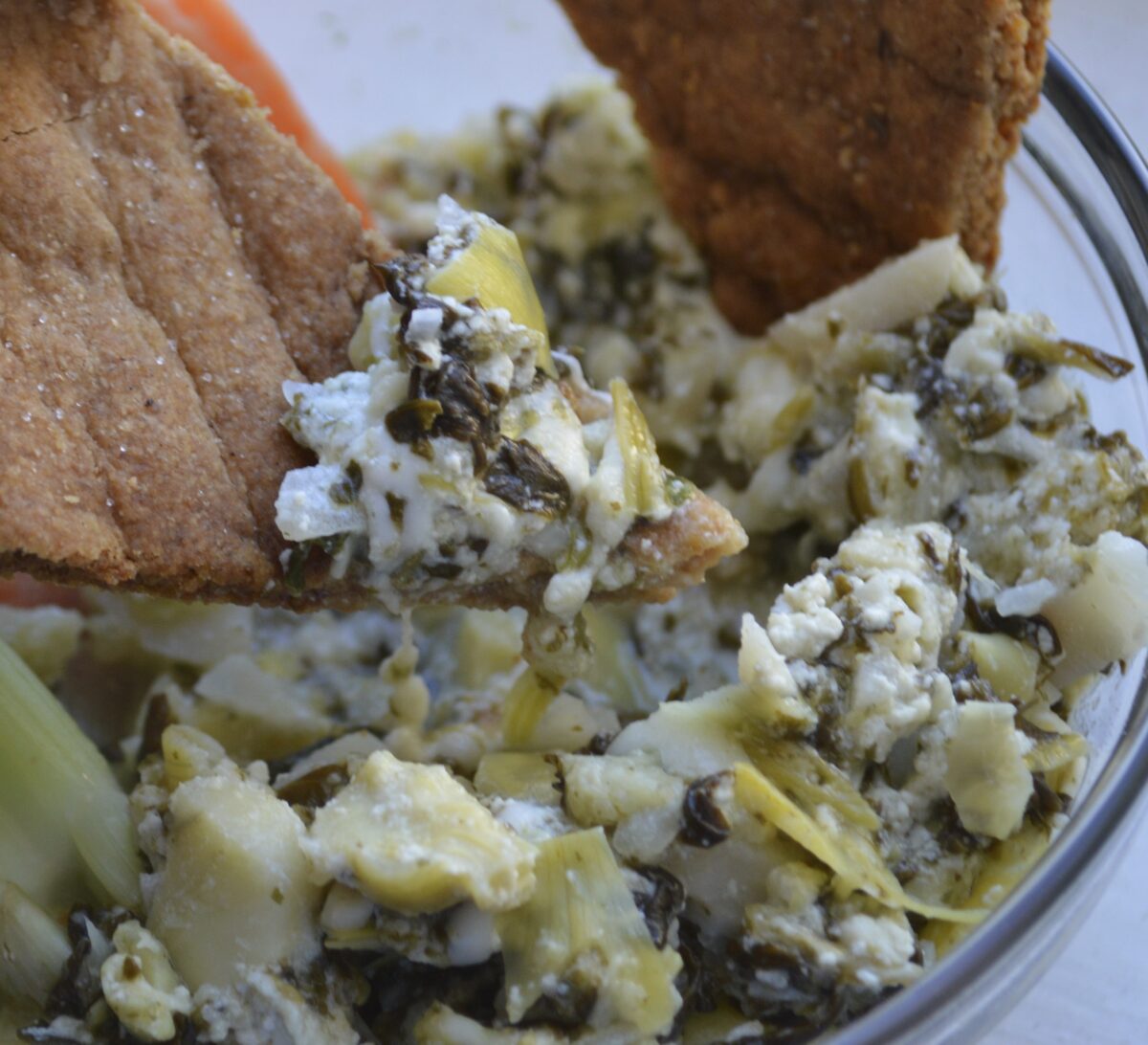 Vegetable dip with crackers being enjoyed.