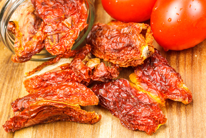 Dried tomatoes and fresh tomatoes on wood.