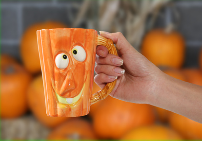 Orange mug with pumpkin face design.