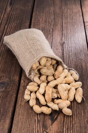 Bag of peanuts spilling onto wooden surface.