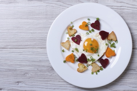 Fried egg surrounded by heart-shaped vegetables.