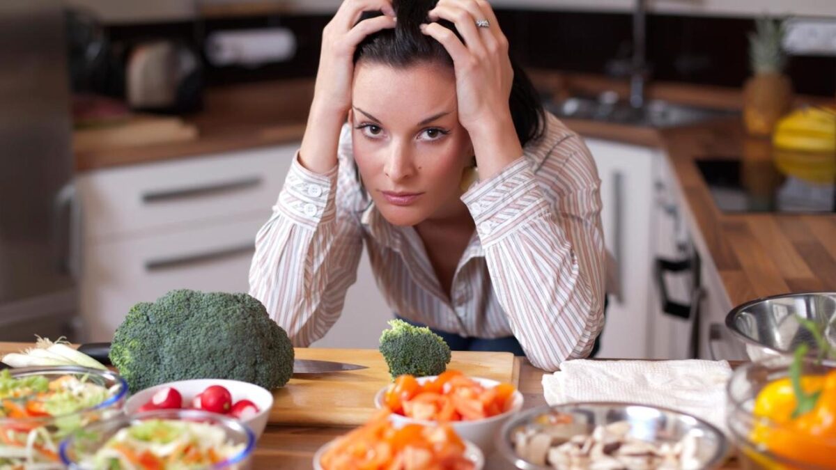 Frustrated woman surrounded by fresh vegetables.