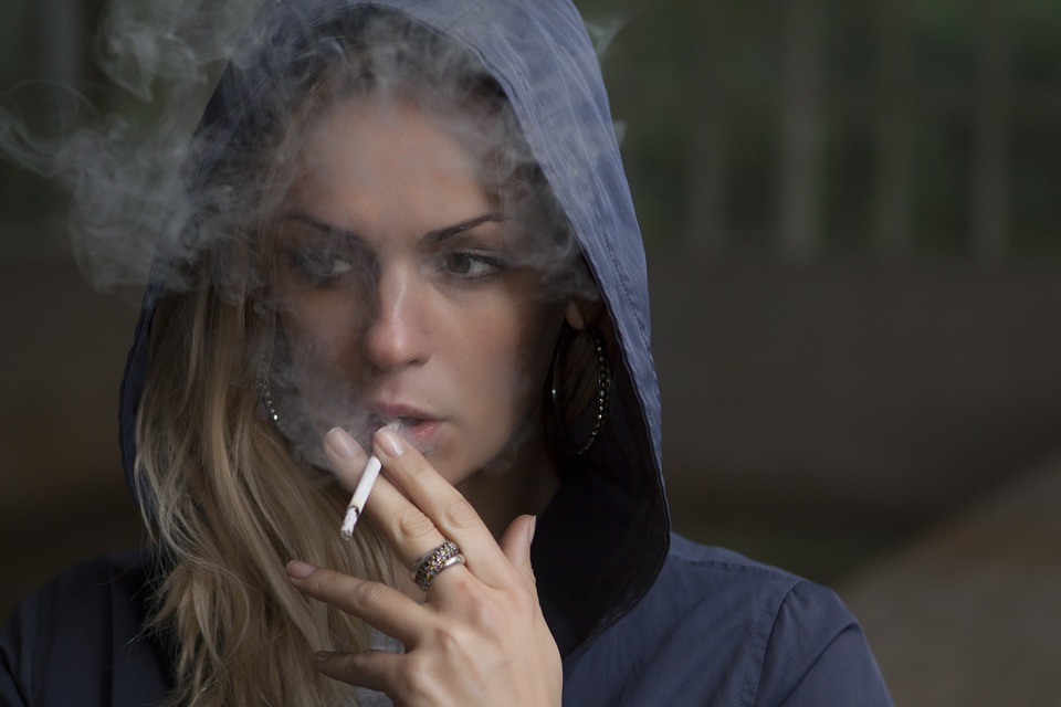 Woman smoking under a hooded jacket.