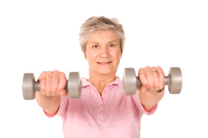 Elderly woman lifting dumbbells, smiling.